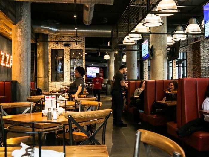 Tall red vinyl booths, modern wood-and-steel tables, and exposed brick made the space feel like a contemporary twist on classic pizza parlor decor.