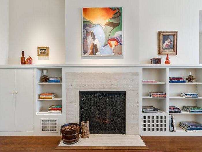 The focal point of the room is a travertine fireplace, with built-in bookshelves on either side.