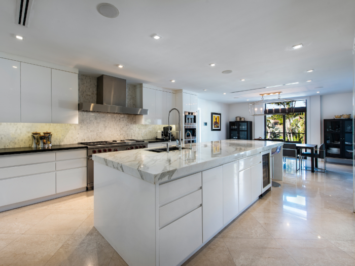 The kitchen features Miele, Wolf, and Sub-Zero appliances, white-lacquered cabinets, and custom countertops made of Calacatta marble.