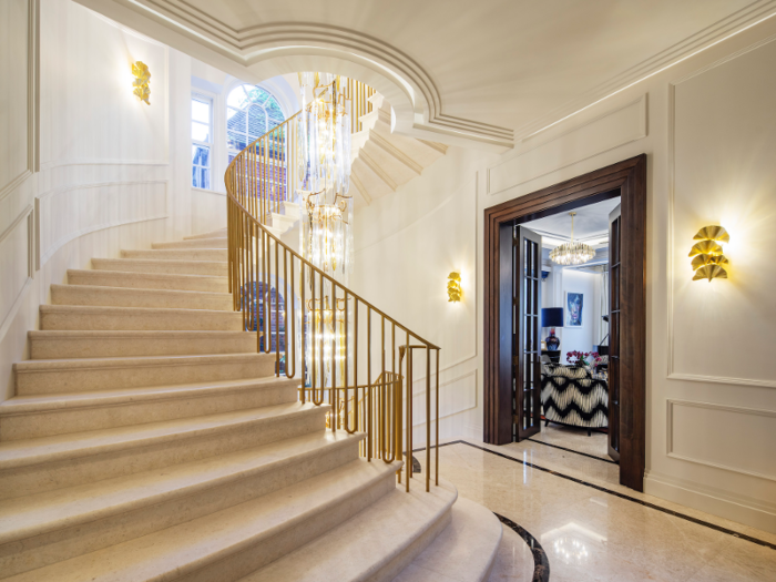 The lavishly decorated home has a double-height entrance hall. The grand hall features a stone staircase and a floor-to-ceiling chandelier.