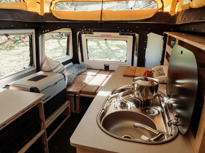 The birch plywood-accented kitchen includes a two-burner stove, sink, and fridge.