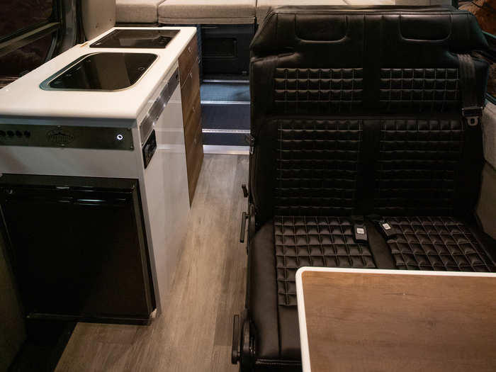 The kitchen has an electric cooktop, sink, refrigerator, storage units, and 700-watt microwave. There