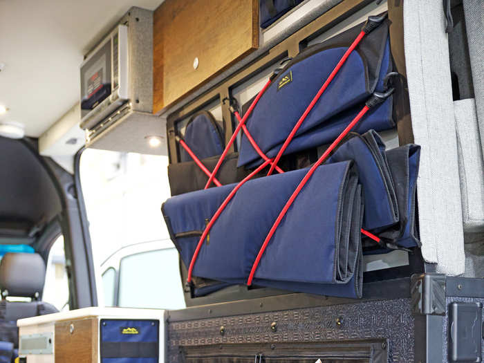 The red bungee straps, pictured below, hold window shades that can be used to deflect heat and maintain internal van temperature, although the windows are also tinted and insulated.