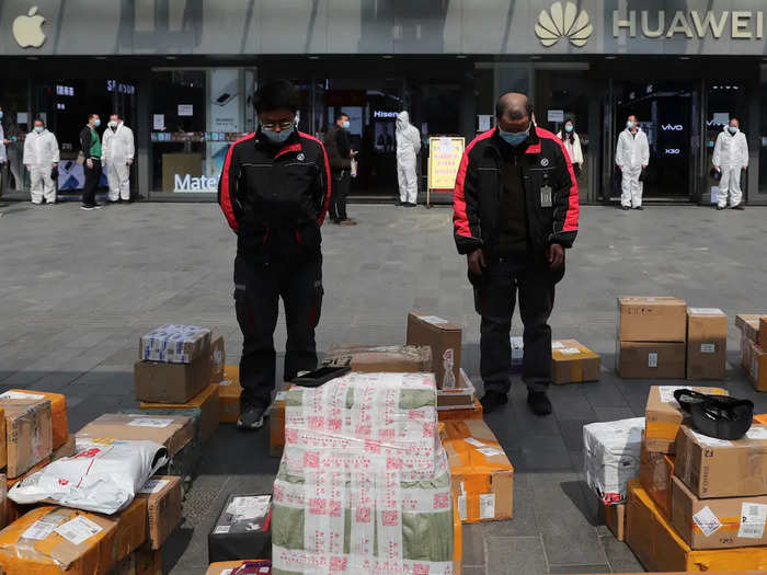 Delivery workers in Wuhan — many of whom still worked during the lockdown — also put down their parcels to bow their heads outside a shopping mall.