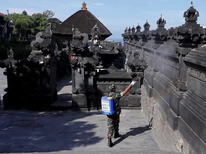 Sitting on a rock in the ocean, the Tanah Lot temple in Bali, Indonesia, is one of the most-visited and photographed temples in Bali, per Lonely Planet, and one of its most recognizable landmarks.