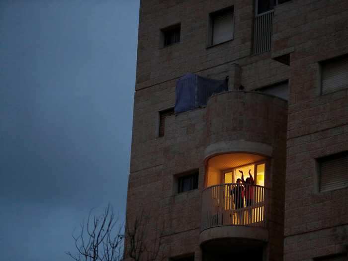 The sun has set in Modiin, Israel, when people step out onto their balconies to cheer for medical staff.