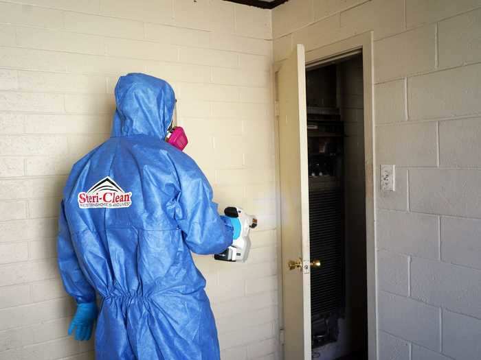 Chalmers uses an electrostatic spray gun to coat surfaces with disinfectant mist.