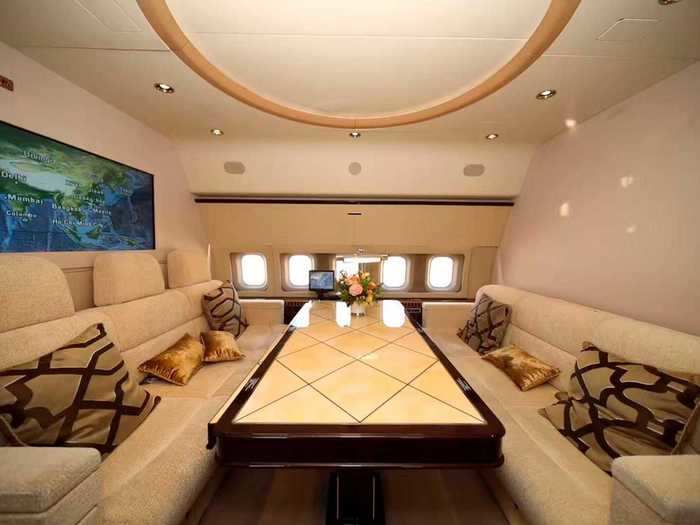 The rear of the aircraft houses the private rooms, including this secluded lounge featuring two three-person divans and a large center table.