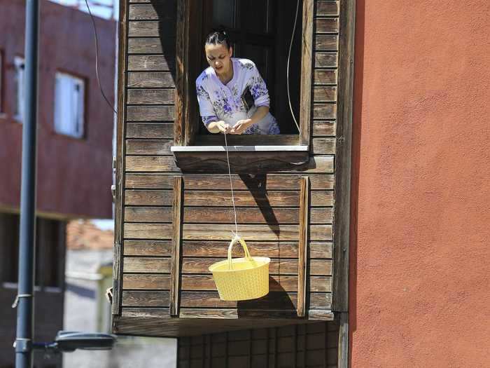 In Istanbul, a woman is photographed lowering a basket from her window to buy bread from a bakery below her.