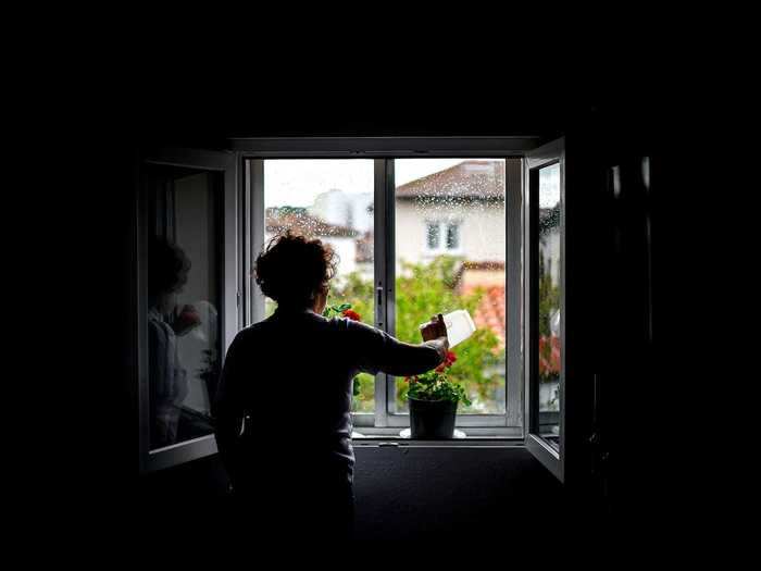 In Burgos, Spain, a woman is seen watering plants from the inside of her home during the country