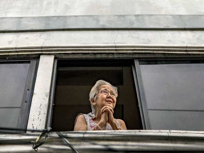 And in the Philippines, a woman waits out of her window for a priest to give blessings on Good Friday.