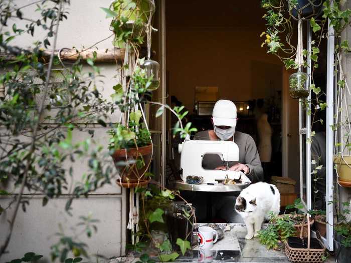 A French costume designer is seen sewing face masks for charity from his apartment window in Paris.