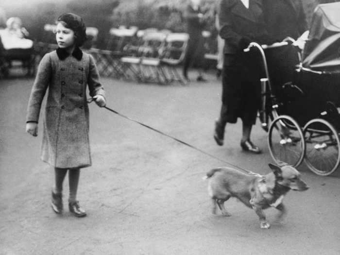 1936: In this picture, a young Elizabeth takes her pet dog for a walk in Hyde Park, London. She spent much of her childhood in 145 Piccadilly, a townhouse located next to The Ritz and bordering the city