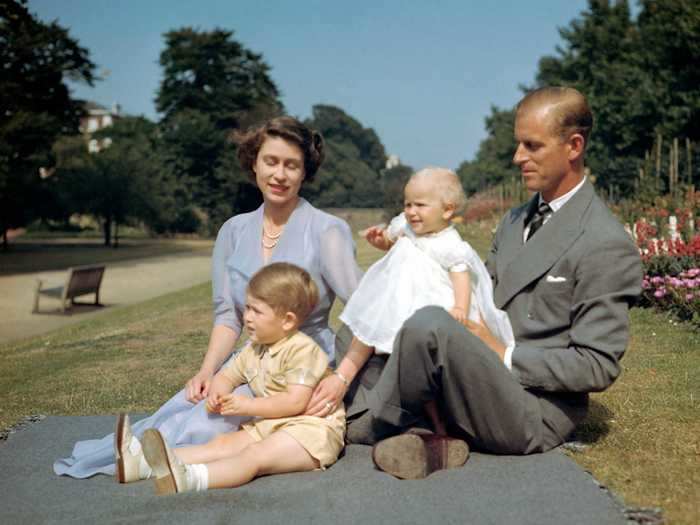 1951: This summer picture shows the soon-to-be Queen, husband Prince Philip, and their children Charles and Anne on the lawn at Clarence House, London.