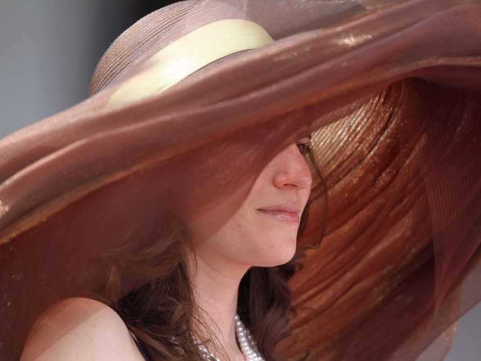 A 2011 attendee kept the sun off her skin in a massive coppery hat.