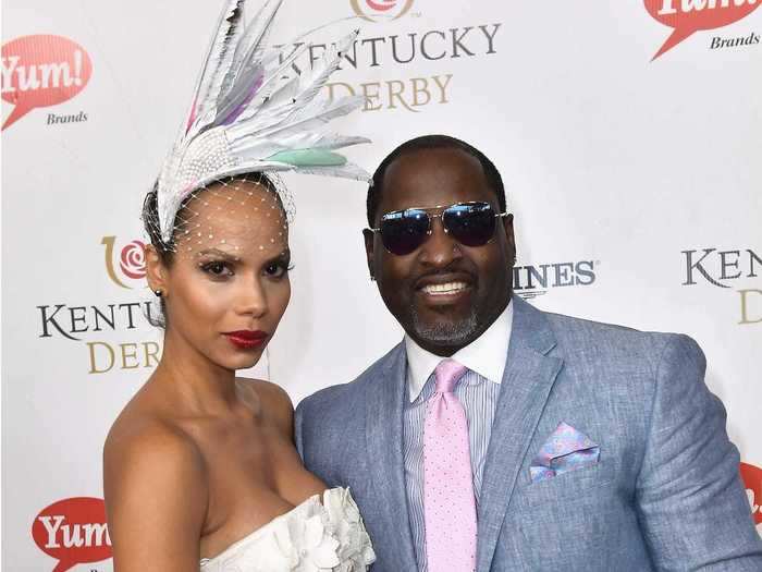 Singer and actor Johnny Gill smiled with a guest who gave off Swan Lake vibes in her gorgeous feathered hat.