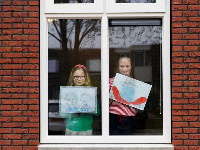 In the Netherlands, two girls, Noalynne and Annelou, held up their drawings in the window. One of them features their "Oma" and "Opa," which are Dutch words for "grandma and grandpa."