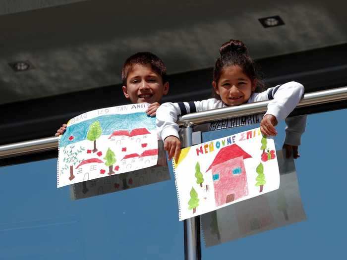 In Greece, Vasilis and Aggelik Bekiaris held up their drawings of colorful houses and trees against a sunny background.