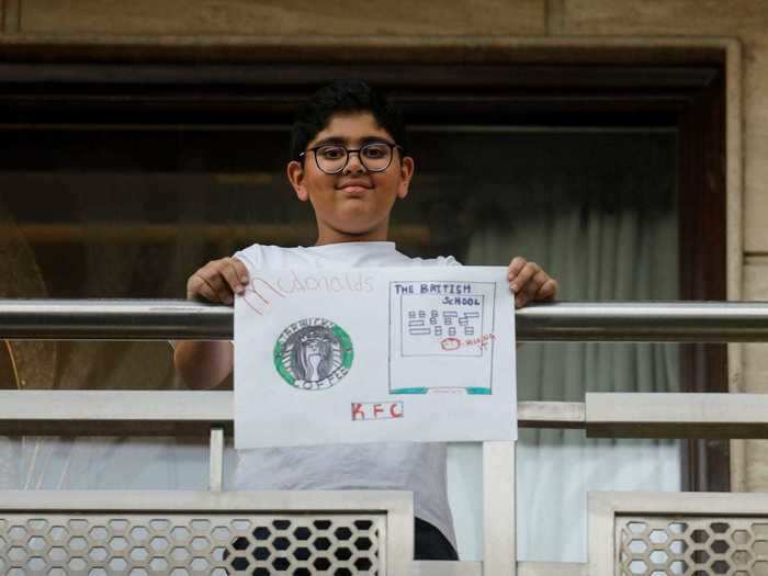 In New Dehli, India, Shaurya Pratap Singh held up his drawing that shows an image of a school alongside the logos for Mcdonalds, Starbucks, and KFC.