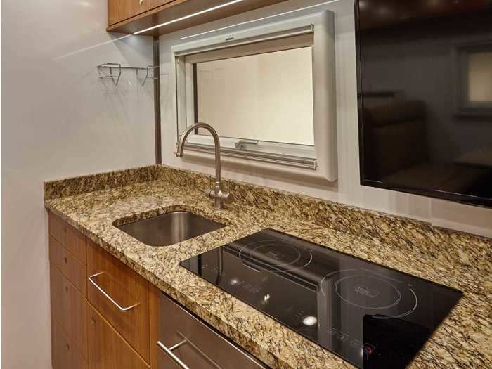 Like many non-mobile homes, the UXV-MAX has a fully equipped kitchen lined with custom granite countertops, a sink, single burner induction cooktop, 6.4 cubic feet refrigerator-freezer, and a convection microwave-oven.