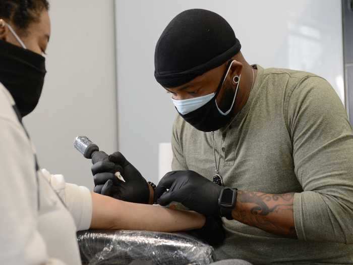 Theo McDaniel, who goes by the name Kutty, tattoos a customer