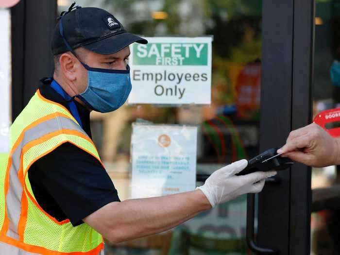 A Costa Vida employee handles payments at the front door of the restaurant. While patio seating is open, only employees are allowed inside.