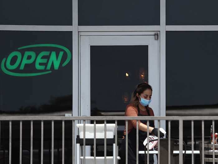 A worker in a mask wipes down tables at Benny