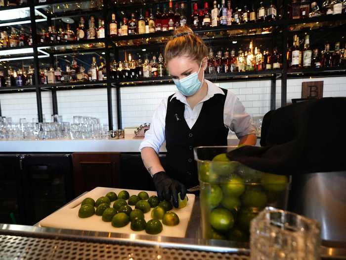 An employee of Federal American Grill slicing limes while wearing a mask on April 24.