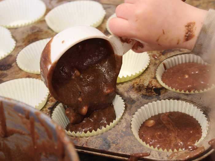 After adding the white chocolate chips, he spooned the batter into cupcake tins.