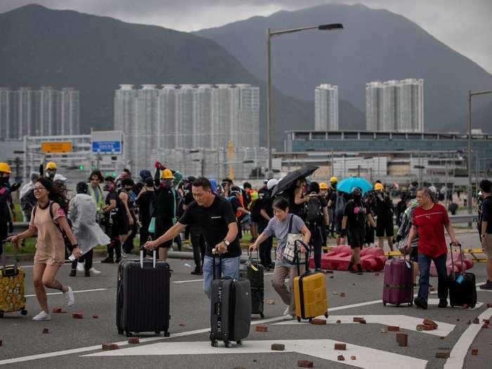 The presence of the protests could be felt widely throughout Hong Kong. In this photo, travelers at the Hong Kong International Airport are seen pushing their luggage past bricks and barriers set up by demonstrators.