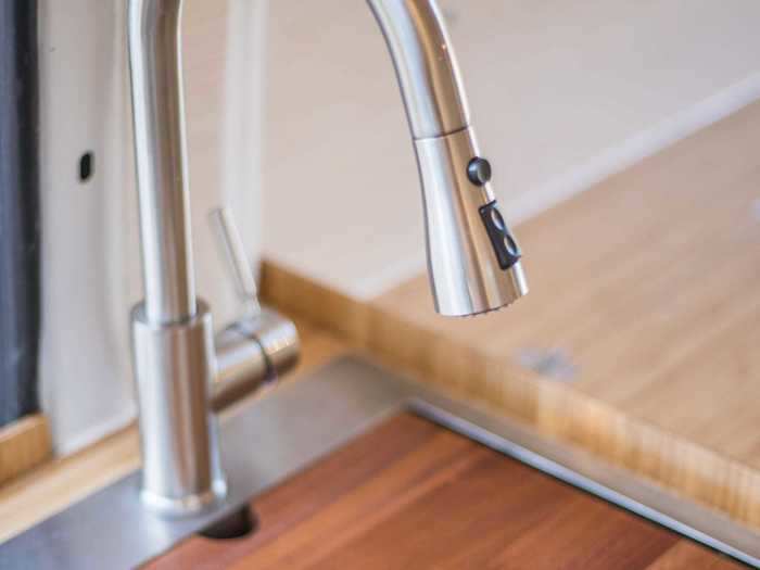 The sink also plays more than one role: it holds an integrated but removable vegetable washing tray, board, and pull-down faucet.