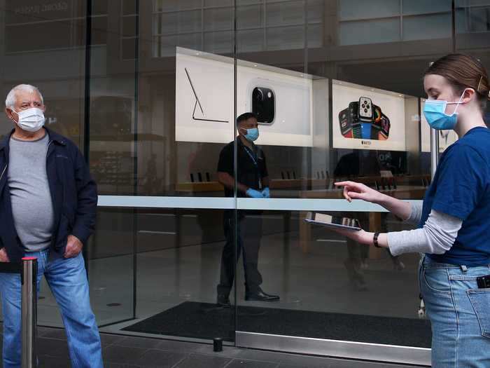 Staff members assist customers prior to entering the Bondi Junction Apple Store by limiting the number of visitors in the store at one time.