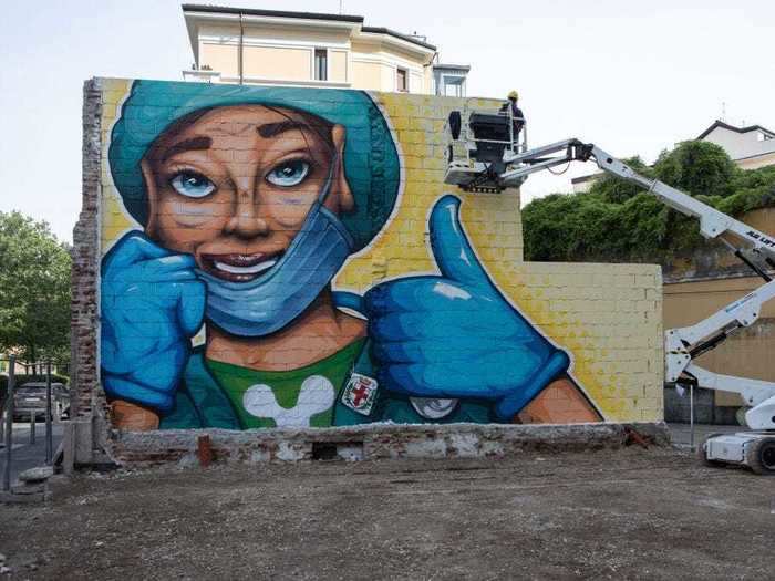 Artist Lapo Fatai used an elevator basket to paint a mural of a nurse giving a thumbs-up in Milan, Italy.