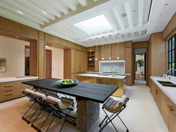 The gourmet kitchen is outfitted with brass details and a skylight.