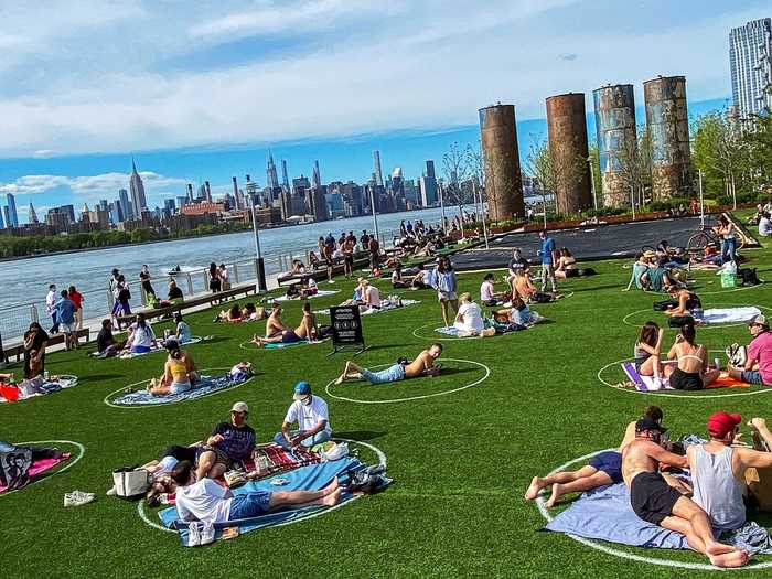 Families, couples, and individuals bring towels to lounge in the sun while keeping at least six feet apart from each other.