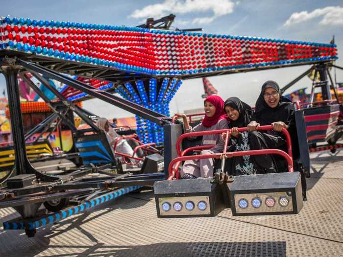 Girls enjoy a carnival ride as people celebrate the festival of Eid at Burgess Park in London, England.