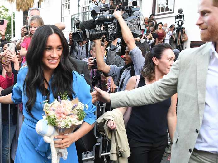 Harry appeared to pull the duchess away from the waiting cameras and fans as they walked the streets of Cape Town.