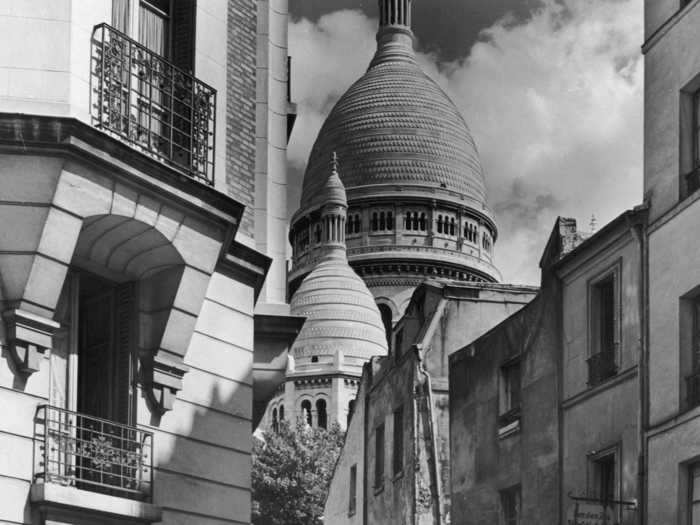 Here, an artist is seen painting the Basilica of Sacré-Cœur, or "The Sacred Heart of Paris," a Roman Catholic Church situated atop a hill that overlooks the city.