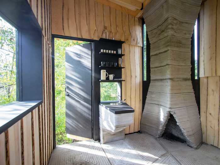 The 21-foot-tall fireplace sits in one corner, next to some shelving and a small sink.