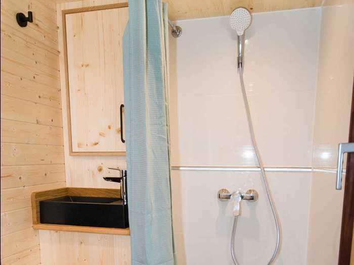 The bathroom has a 2.6-foot by 2.6-foot shower space, a dry toilet, a sink, and storage spaces, including a closet.