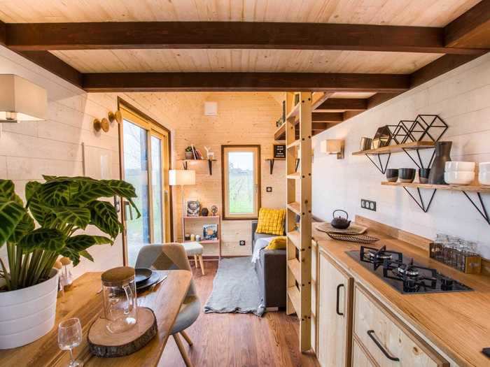 Wooden details accent the interior of the tiny home, including the ceiling, floors, and kitchen …