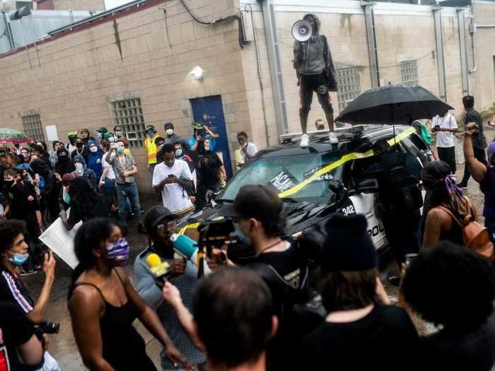 A small group of people stood on police cars and began vandalizing the police station, according to local media outlets.