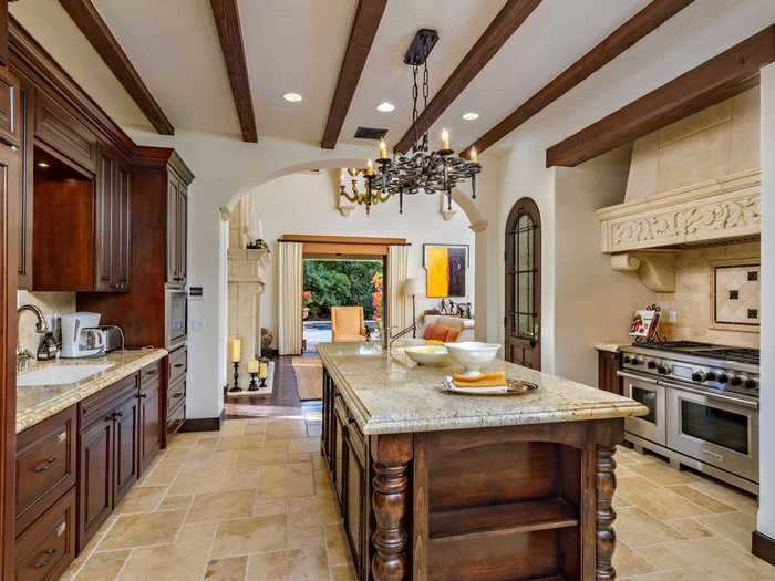 The adjacent kitchen has a large stone and wood island ...