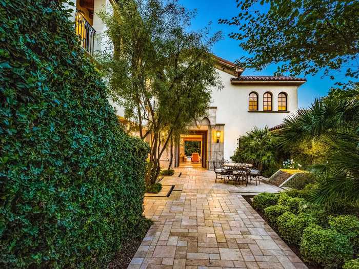 The house is built in the Spanish Colonial style, with private terraces, stucco walls, and a terracotta roof.