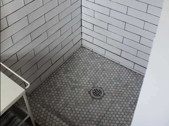 The bathroom has a full-length mirror, sink, and three-foot by three-foot shower space.