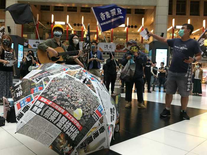 Here, a group of people are seen holding banners in support of Hong Kong