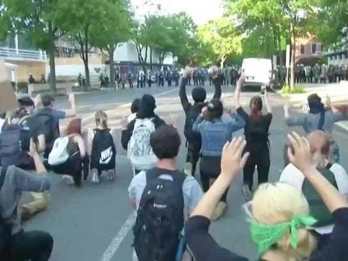 At one point, protesters knelt before the wall of police with their hands raised.