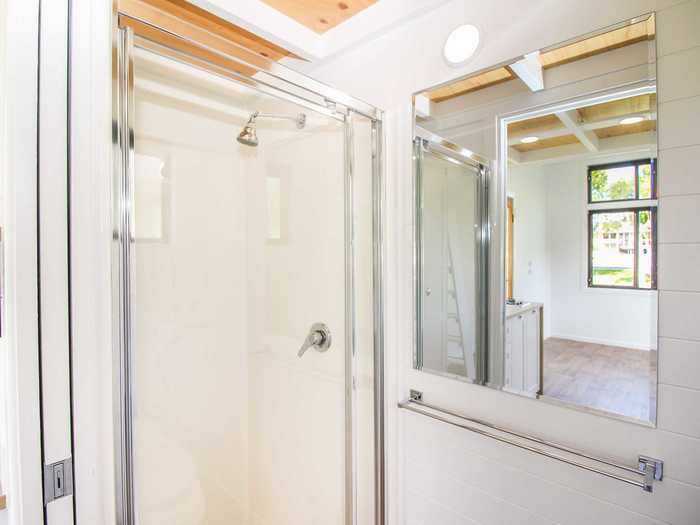 The bathroom, which is by the kitchen, has a composting toilet, full size shower, towel rack, and large mirror.