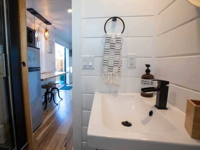 The bathroom sits at one end of the container home next to the kitchen, while the bedroom sits at the other end beside the living room.