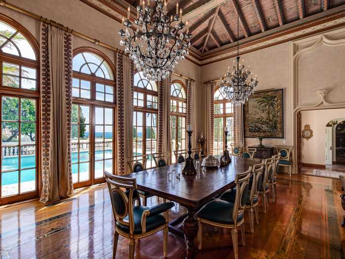 The grand dining room features floor-to-ceiling windows with poolside views.